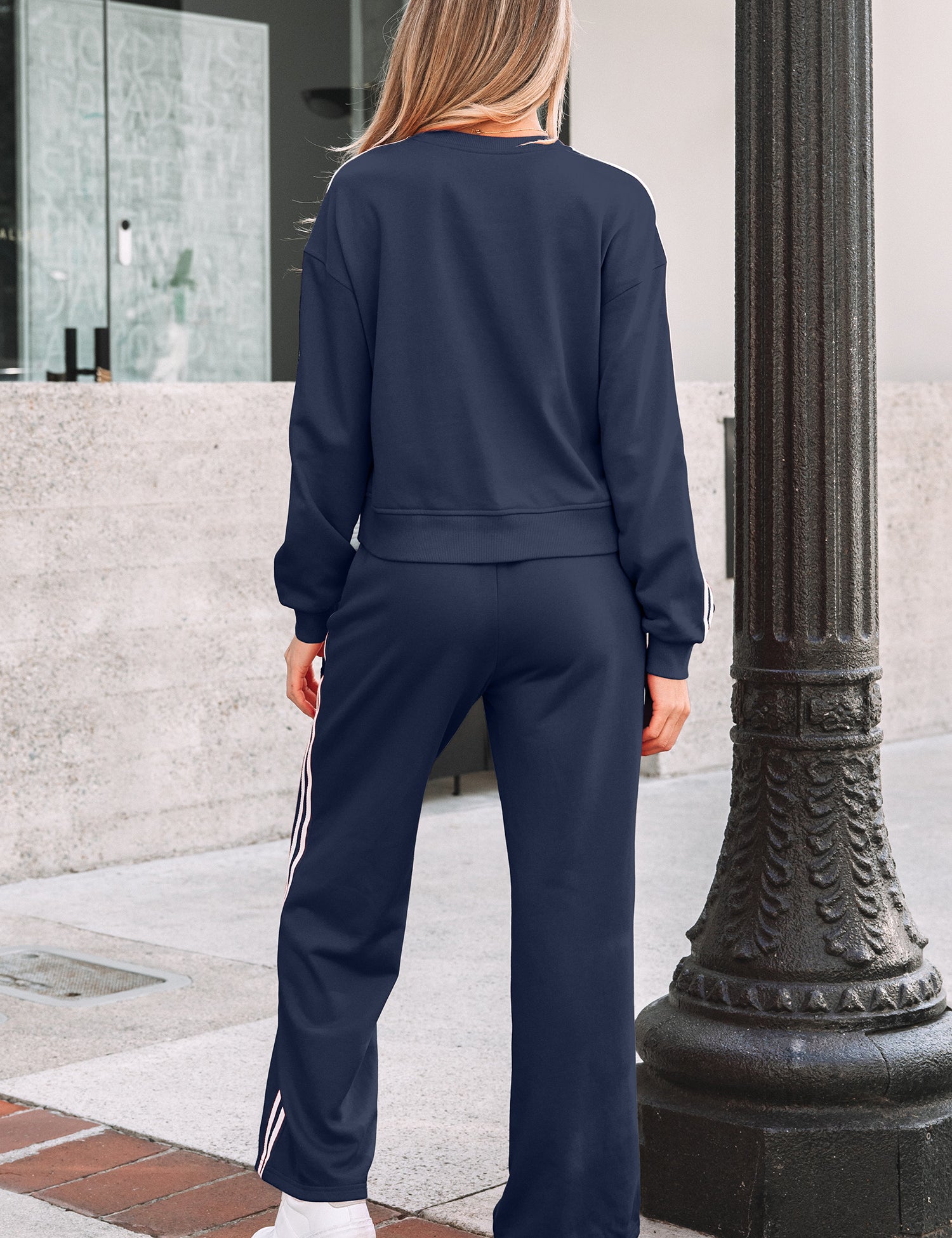 Woman wearing a navy tracksuit standing outdoors near a building entrance.