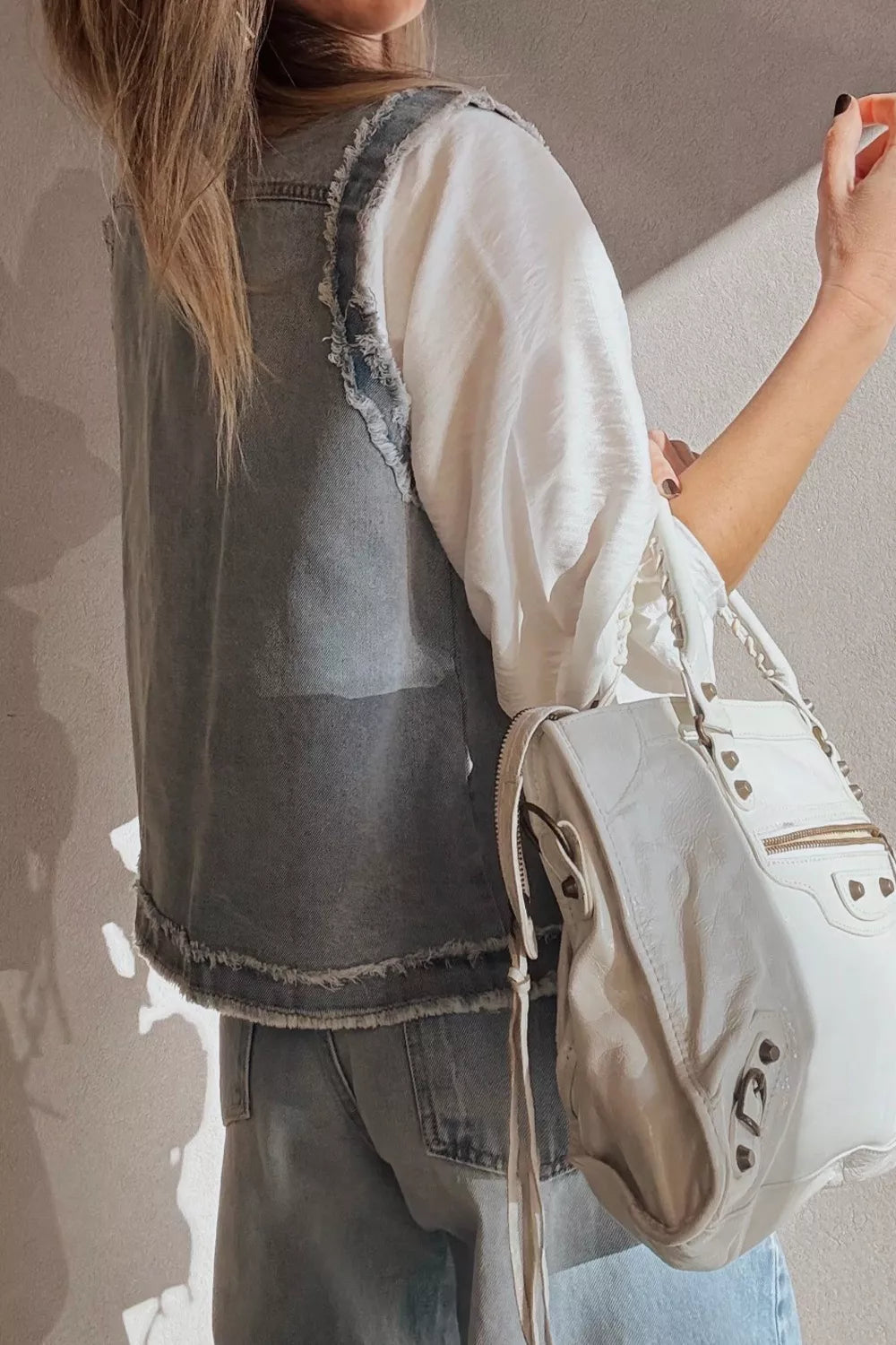White leather backpack with silver hardware and frayed edge flap design