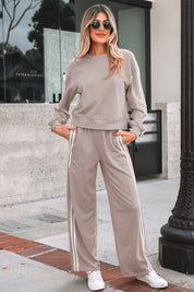 Woman wearing a beige tracksuit with white stripes outdoors.