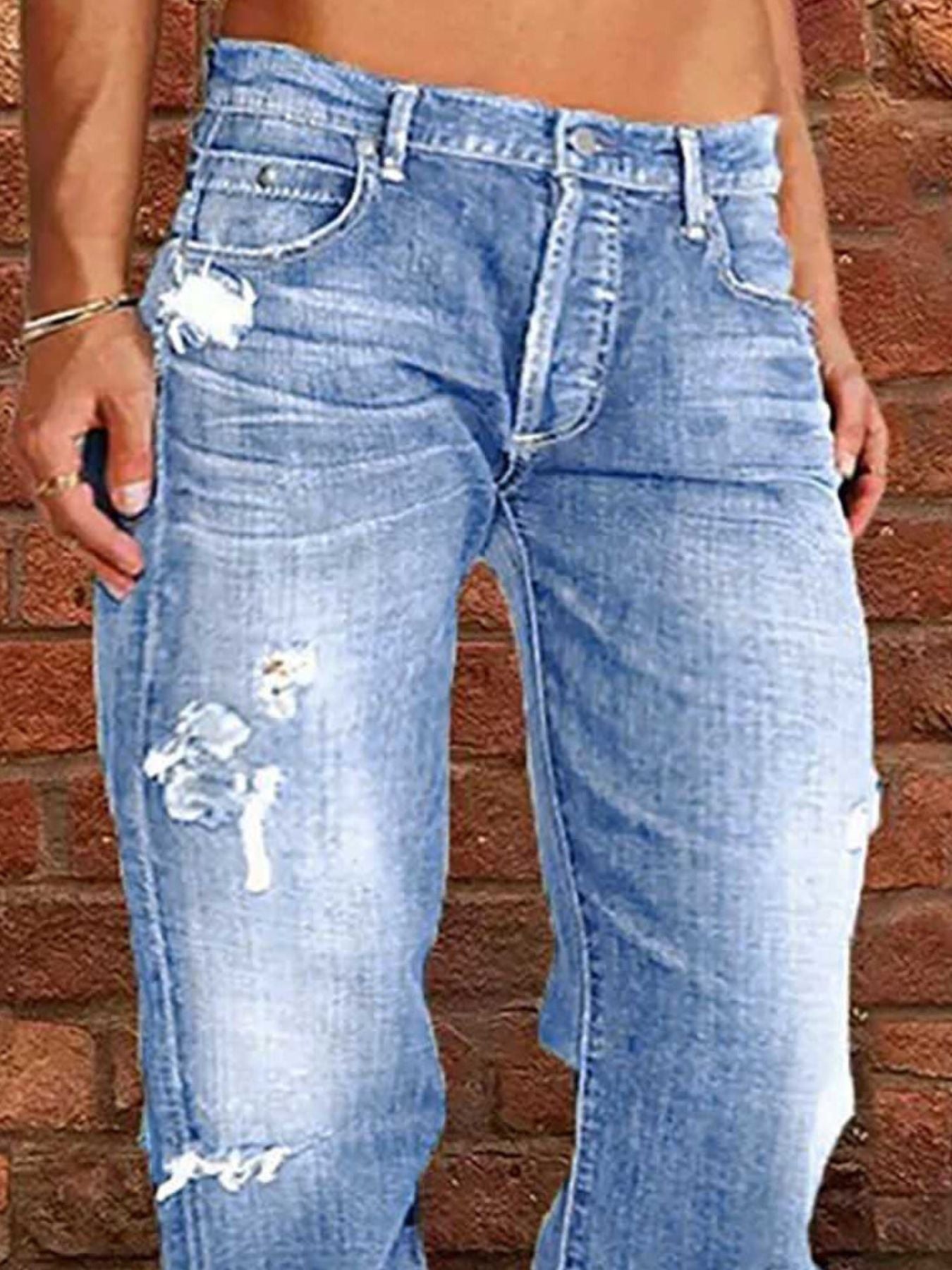 Distressed loose fit light-wash denim jeans with frayed thigh patches