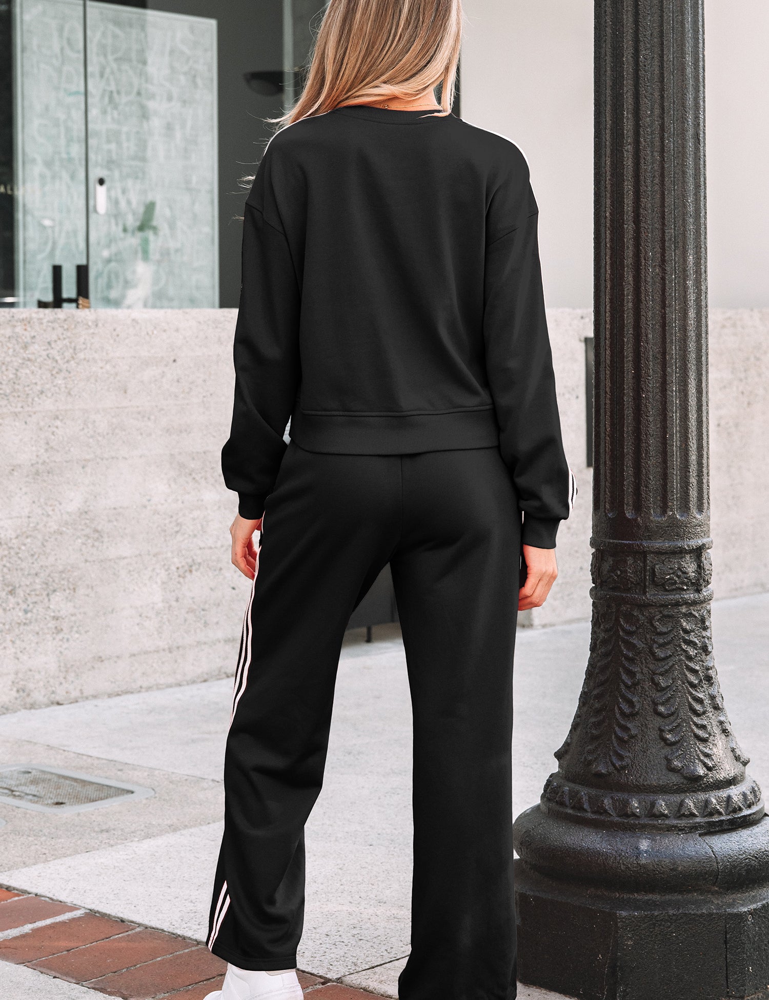 Person wearing a black tracksuit standing next to a decorative lamp post.