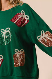 Green sequined gift box sweater with white bows and red accents