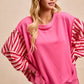 Pink oversized BiBi French terry sweatshirt with ruffled red and white striped sleeves