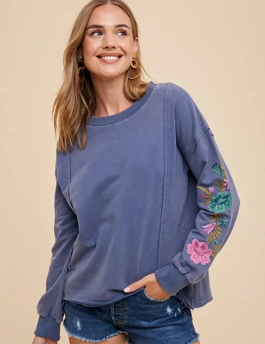 Blue embroidered long sleeve French terry top with denim shorts and gold hoops