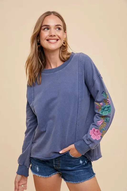 Blue embroidered long sleeve French terry top with denim shorts and gold hoops