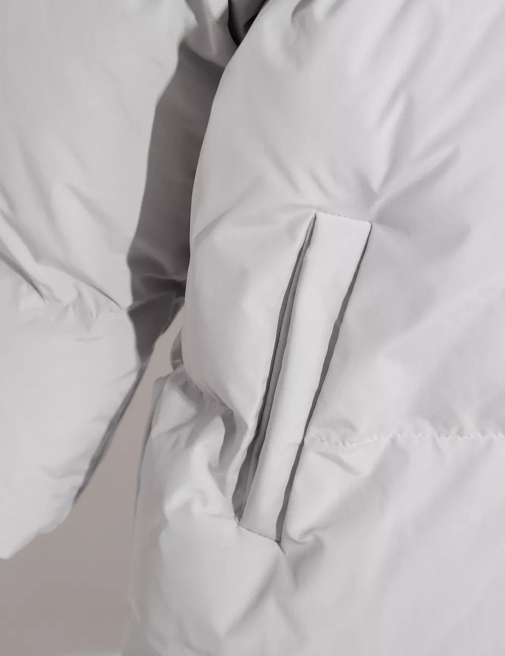 White pocketed zip-up hooded puffer jacket with silver zipper and gray piping