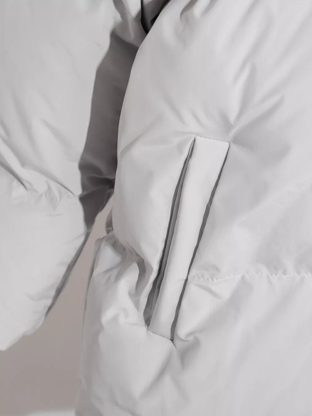 White pocketed zip-up hooded puffer jacket with silver zipper and gray piping