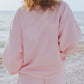 Person wearing relaxed fit pink sweatshirt at beach