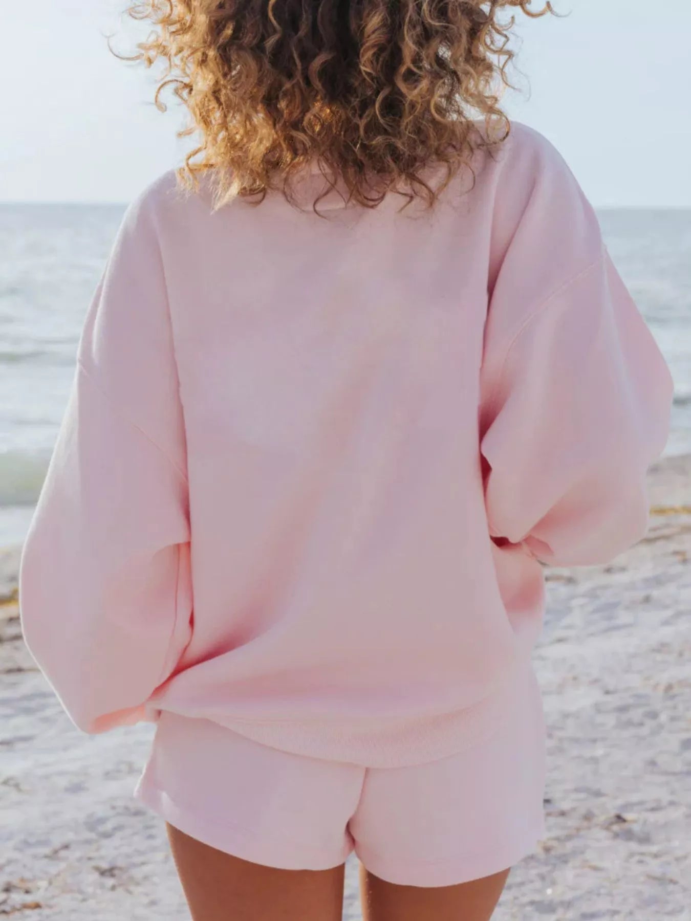 Person wearing relaxed fit pink sweatshirt at beach