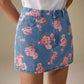 Floral print denim mini skirt with pink roses and green leaves on blue denim