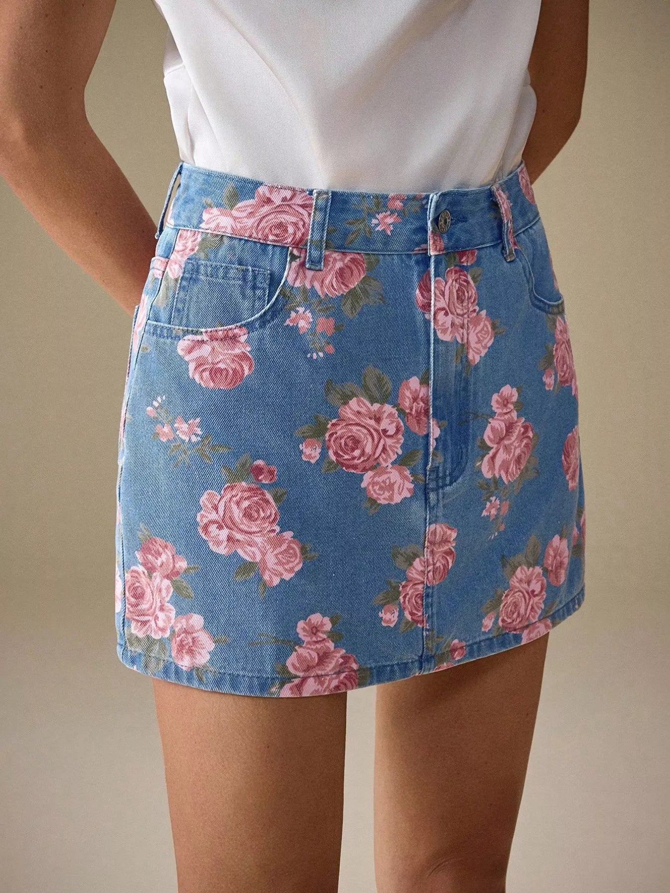 Floral print denim mini skirt with pink roses and green leaves on blue denim