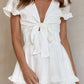 White tie-front mini dress with ruffled sleeves and smocked waist