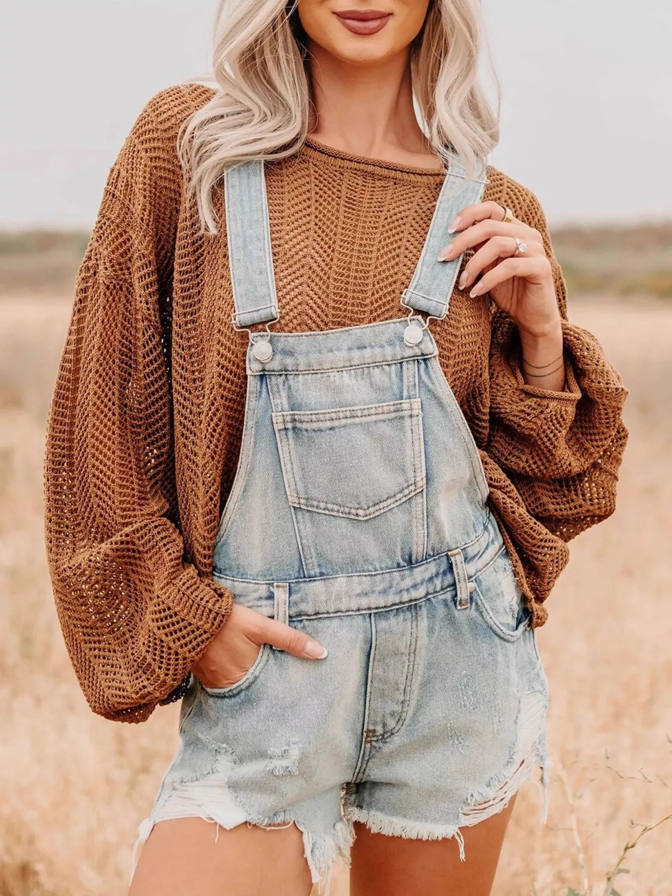 Distressed denim overalls shorts in light-wash with frayed hem and adjustable straps