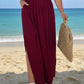 Woman in Daverri Fashions maroon V-neck maxi dress with side slit on beach