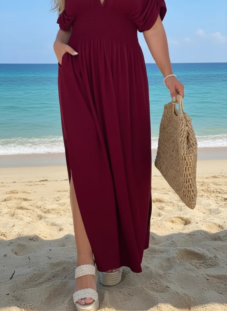 Woman in Daverri Fashions maroon V-neck maxi dress with side slit on beach