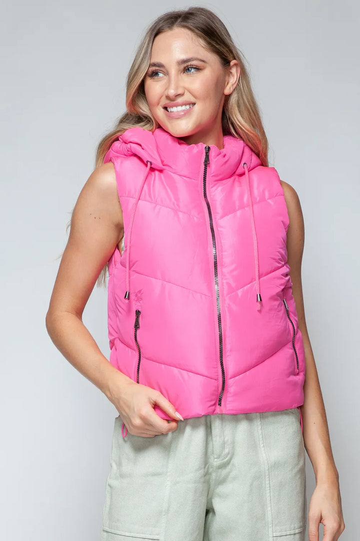 A woman wearing a pink vest jacket and jeans
