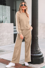 Woman wearing a beige tracksuit with white stripes standing on a sidewalk.