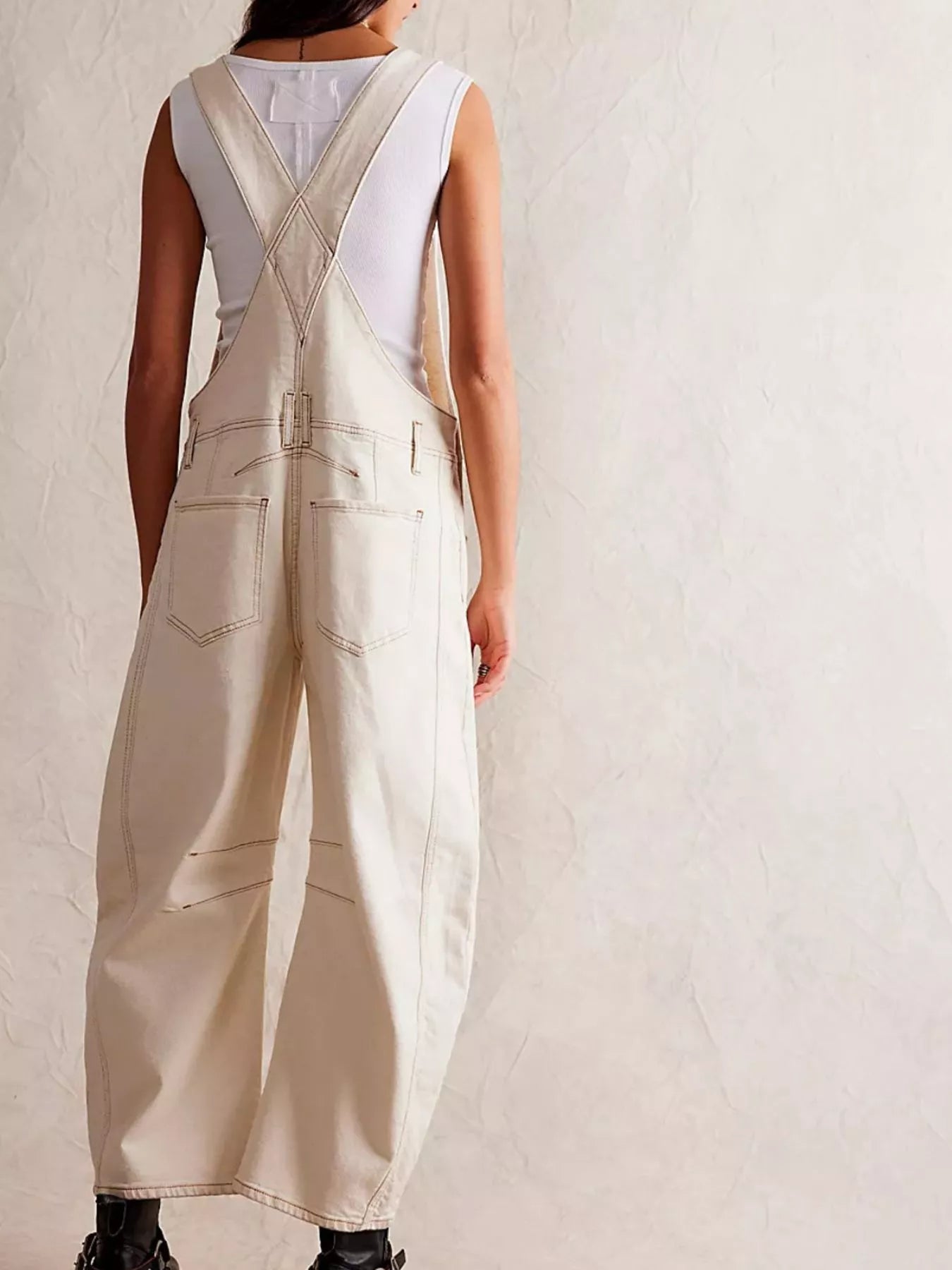 Back view of cream wide-leg denim overalls with cross-back straps