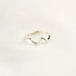 Silver ring with wavy design on a light beige background