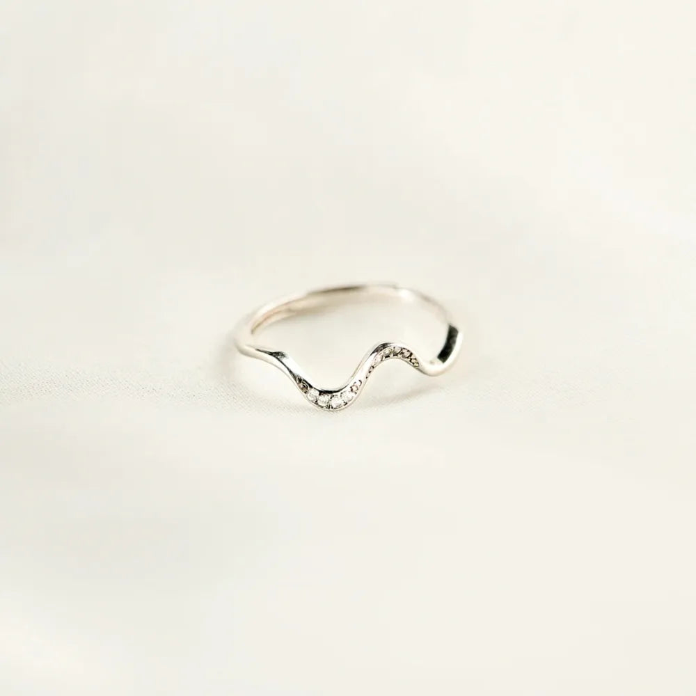 Silver ring with wavy design on a light beige background