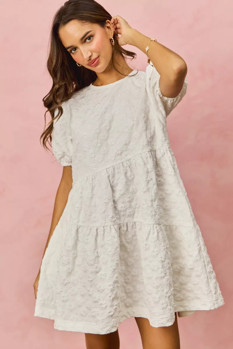 White SO ME floral jacquard diagonal tiered mini dress with textured fabric, short puffed sleeves, and round neckline