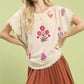 Umgee linen blend top with cream fabric, frayed edges, and vibrant pink, red, purple floral embroidery
