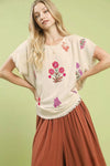 Umgee linen blend top with cream fabric, frayed edges, and vibrant pink, red, purple floral embroidery