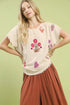 Umgee linen blend top with cream fabric, frayed edges, and vibrant pink, red, purple floral embroidery
