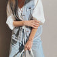 Light gray leather handbag with silver hardware on frayed denim vest