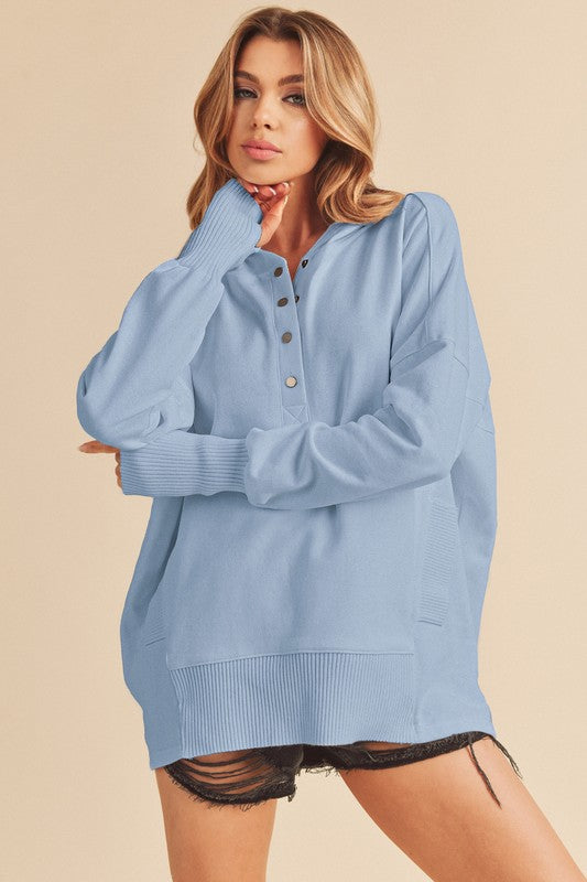 Woman wearing a light blue hoodie  over a black outfit on a beige background