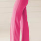 Bright pink high-waisted bootcut pants with sleek fabric and vertical seams