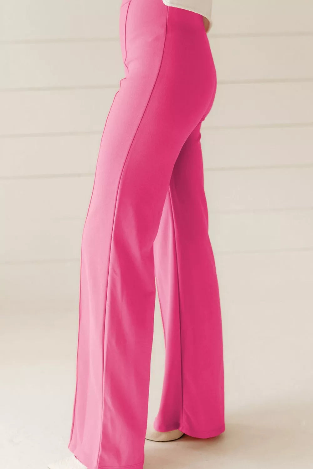 Bright pink high-waisted bootcut pants with sleek fabric and vertical seams
