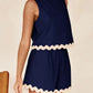 Navy blue Daverri sleeveless romper with cream scalloped trim