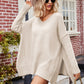 Cream-colored oversized V-neck slit exposed seam sweater with ribbed cuffs
