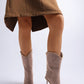 Brown knee-high boots worn with a brown dress on a white background