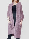 Woman wearing a soft lavender chunky knit open-front cardigan with a waffle texture and large side pockets, paired with jeans.