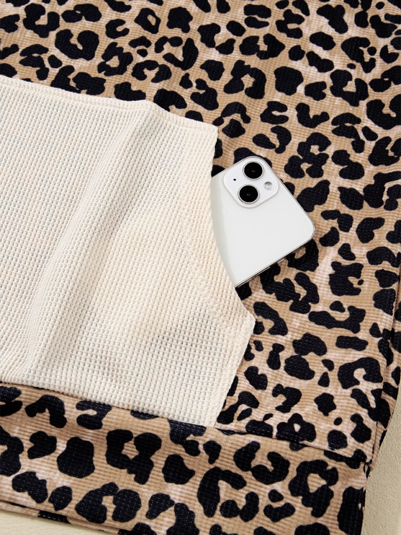 White iPhone 13 on leopard print hoodie fabric