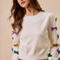 White SO ME Mardi Gras knit sweater with colorful sequined bows