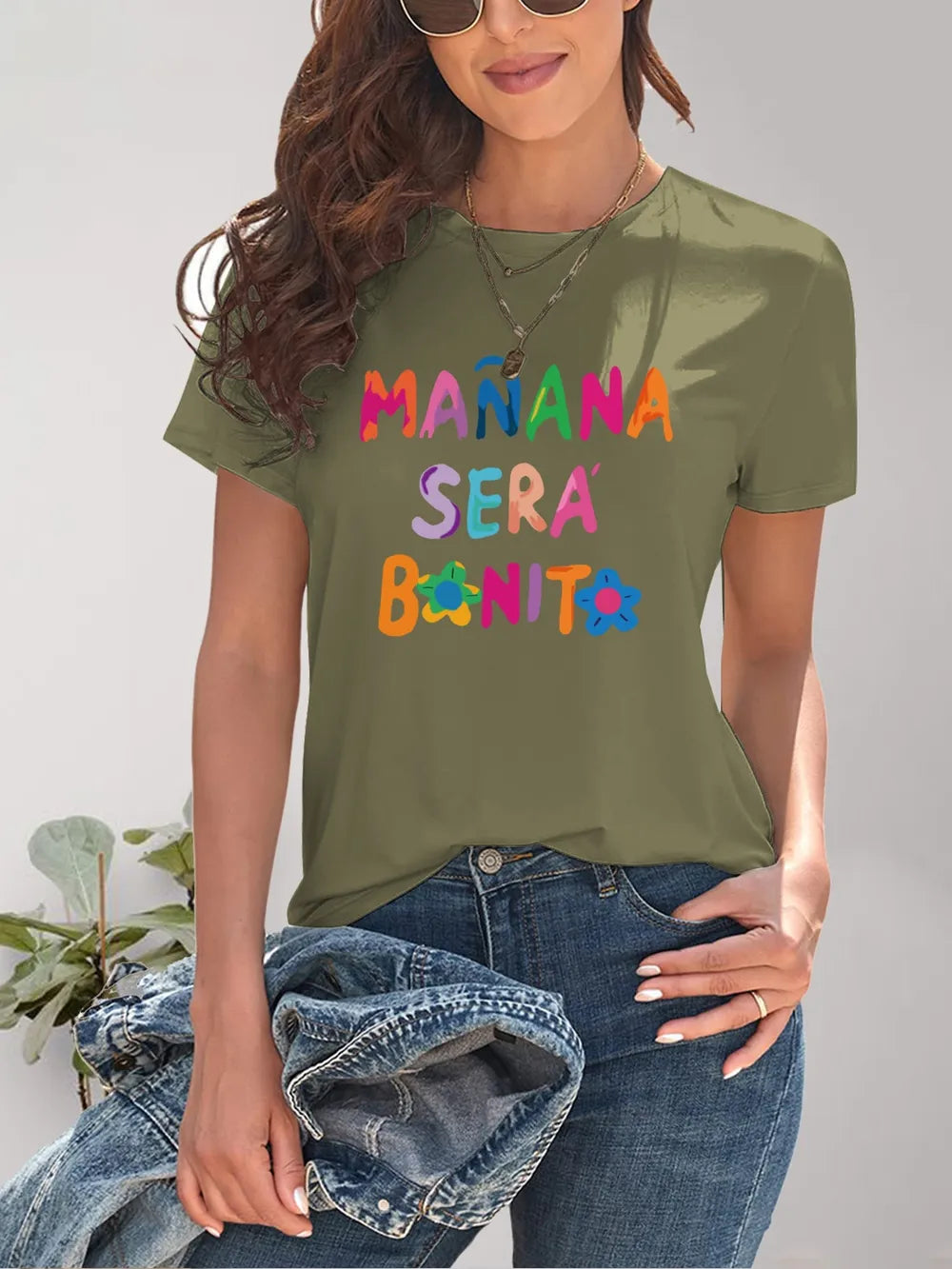 Olive green short-sleeve t-shirt with Manana Sera Bonito graphic and distressed denim jeans