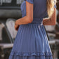 Tie-front mini dress in soft blue with tiered ruffles, smocked waist, and flutter sleeves
