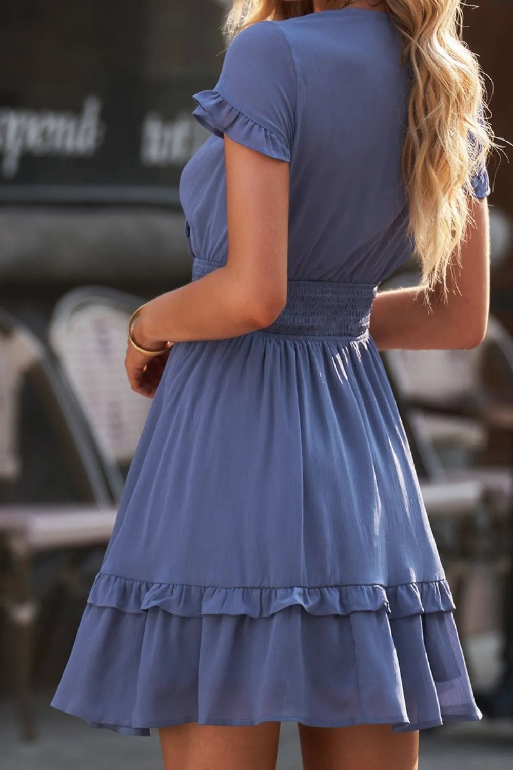 Tie-front mini dress in soft blue with tiered ruffles, smocked waist, and flutter sleeves