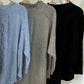 Three full-size cable-knit sweaters in blue, gray, black on hangers
