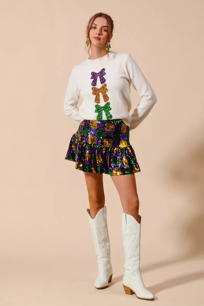 White long-sleeved sweater with Mardi Gras purple, gold, green sequined bows