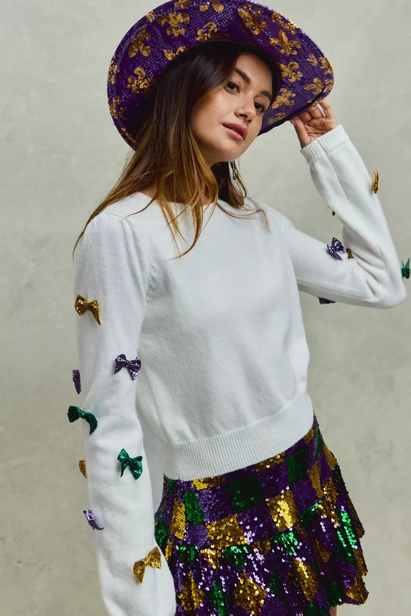 White SO ME Mardi Gras sweater with purple, gold, green sequined bows