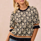 BiBi Textured Rose Knit Top with black and cream floral pattern and ruffled cuffs
