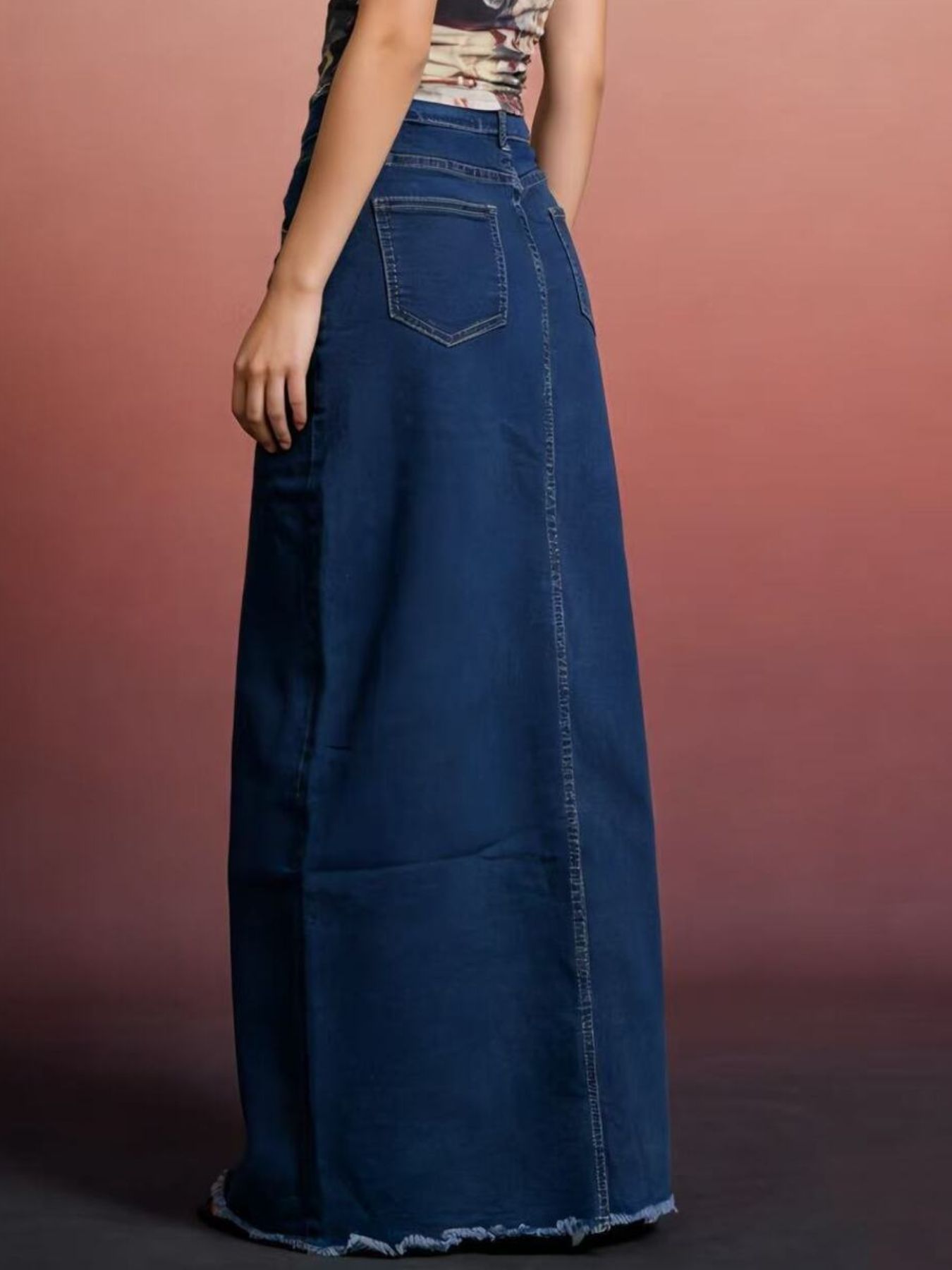 Raw hem maxi denim skirt back view with dark blue denim pocket and frayed hem