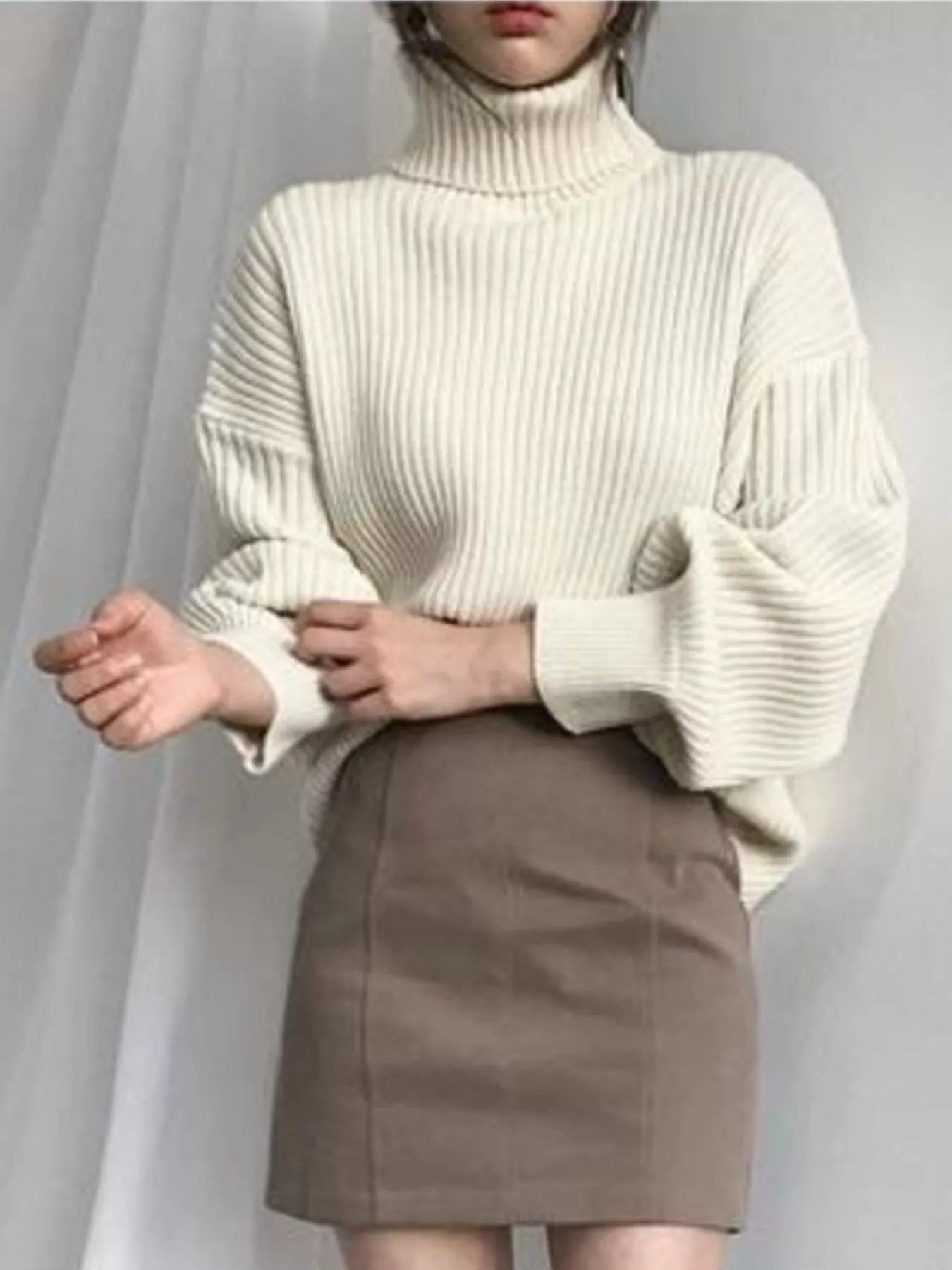 Cream-colored ribbed knit oversized turtleneck sweater with voluminous sleeves