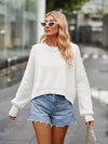 White dropped shoulder knit top with ribbed cuffs, paired with distressed denim shorts