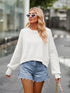 White dropped shoulder knit top with ribbed cuffs, paired with distressed denim shorts