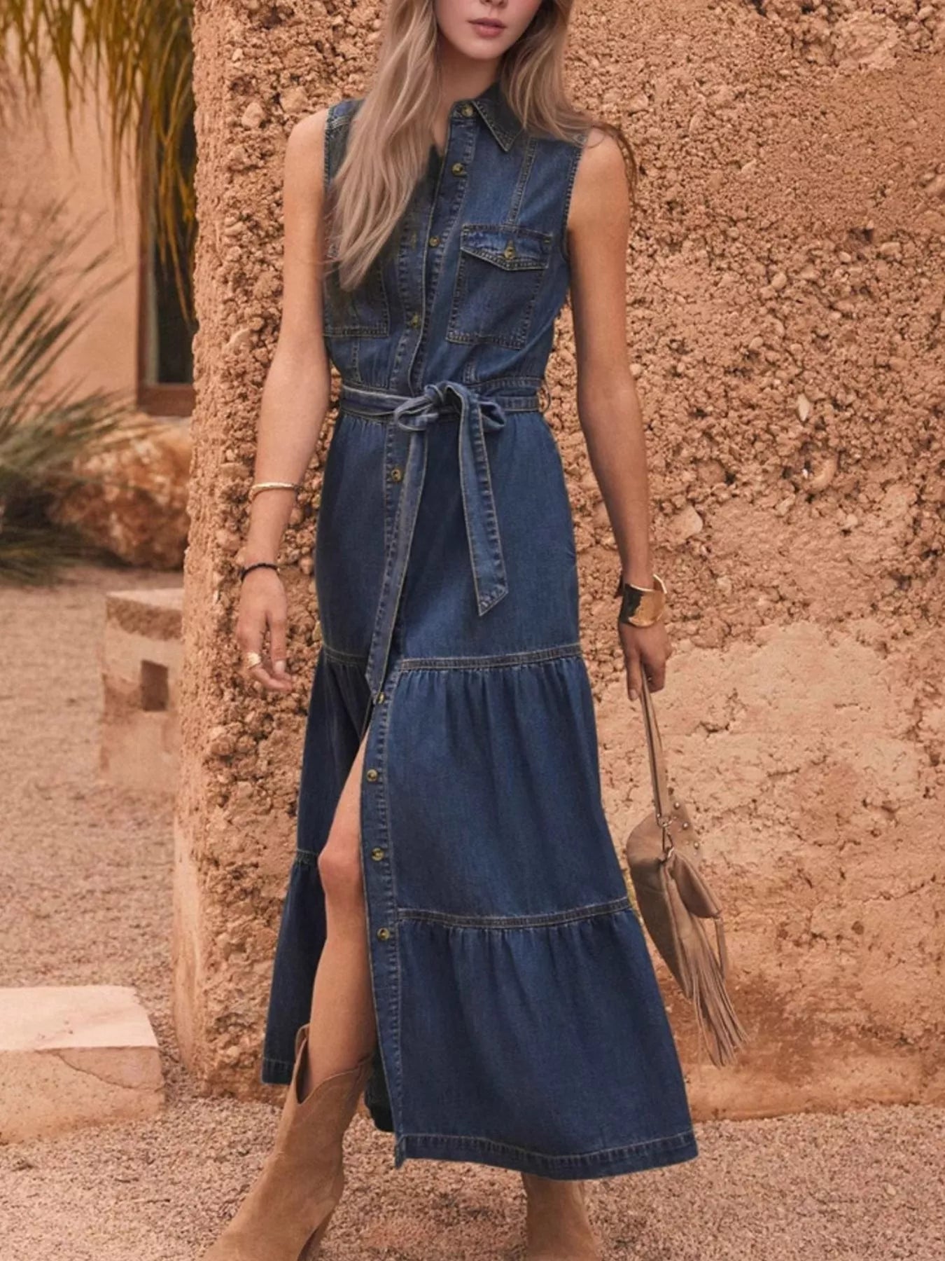 Button front sleeveless blue denim dress with tiered skirt and tied waistband